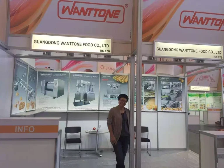 A person at the Wanttone exhibition booth displaying machinery and biscuits in Malaysia