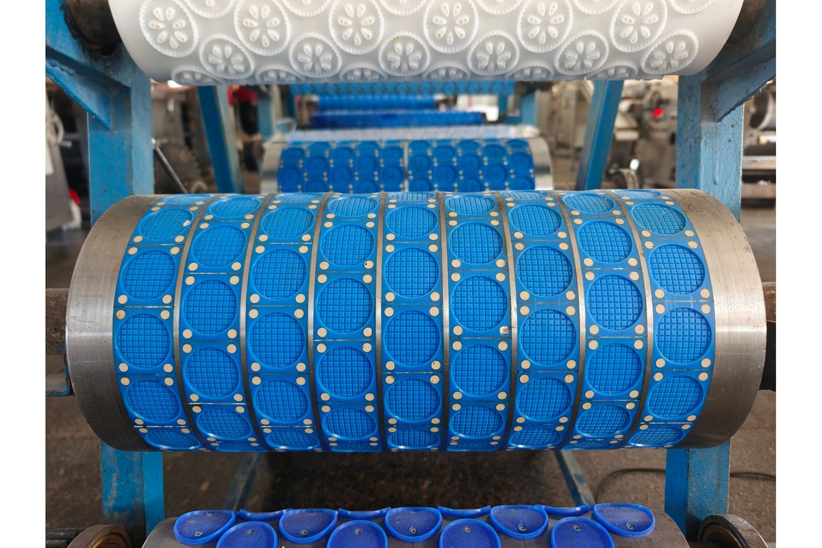 Original workshop photograph of blue plastic biscuit mould cavities mounted around a roller